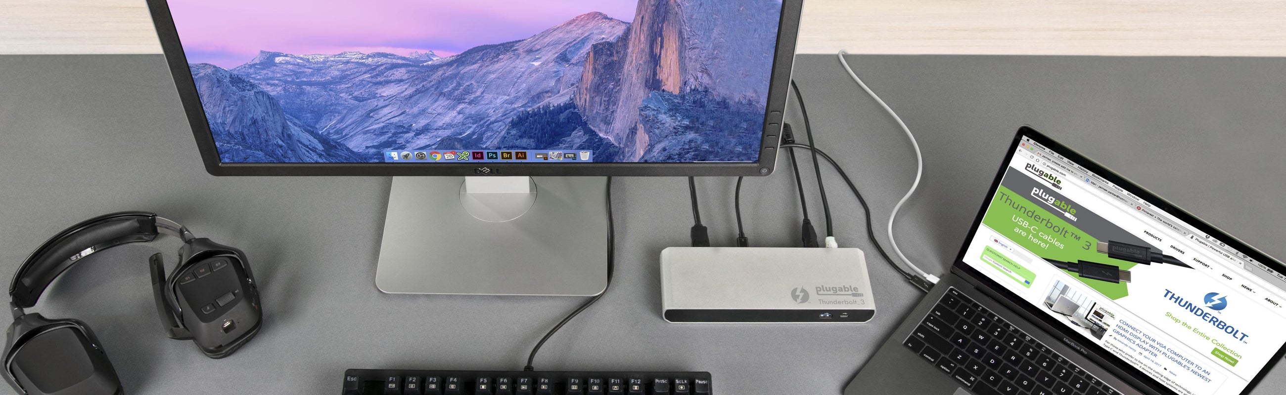The TBT3-UD1-83 Thunderbolt Single Display dock plugged into a monitor with a laptop host, mouse, keyboard, mobile phone and pear of headphones