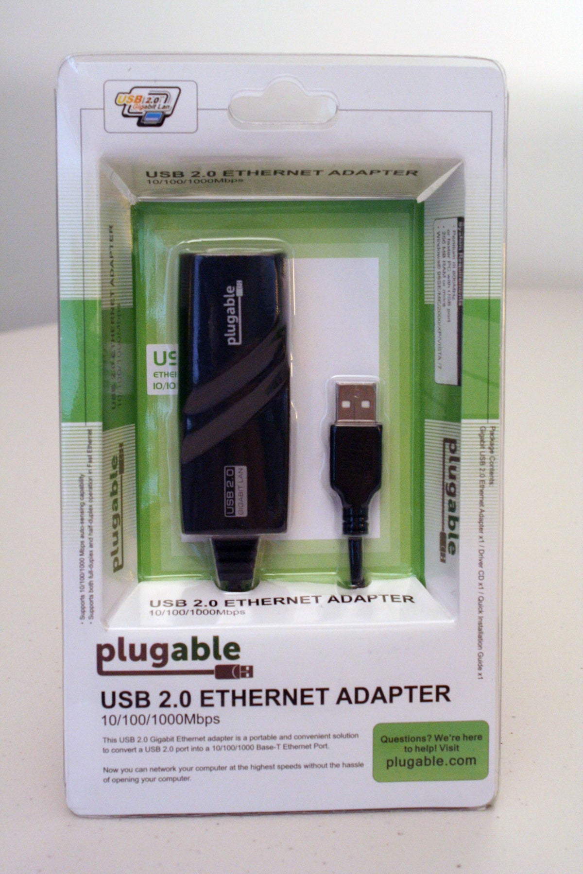 Plugable USB 2.0 to 10/100/1000Mbps Gigabit Ethernet adapter in retail packaging with system requirements and contents.
