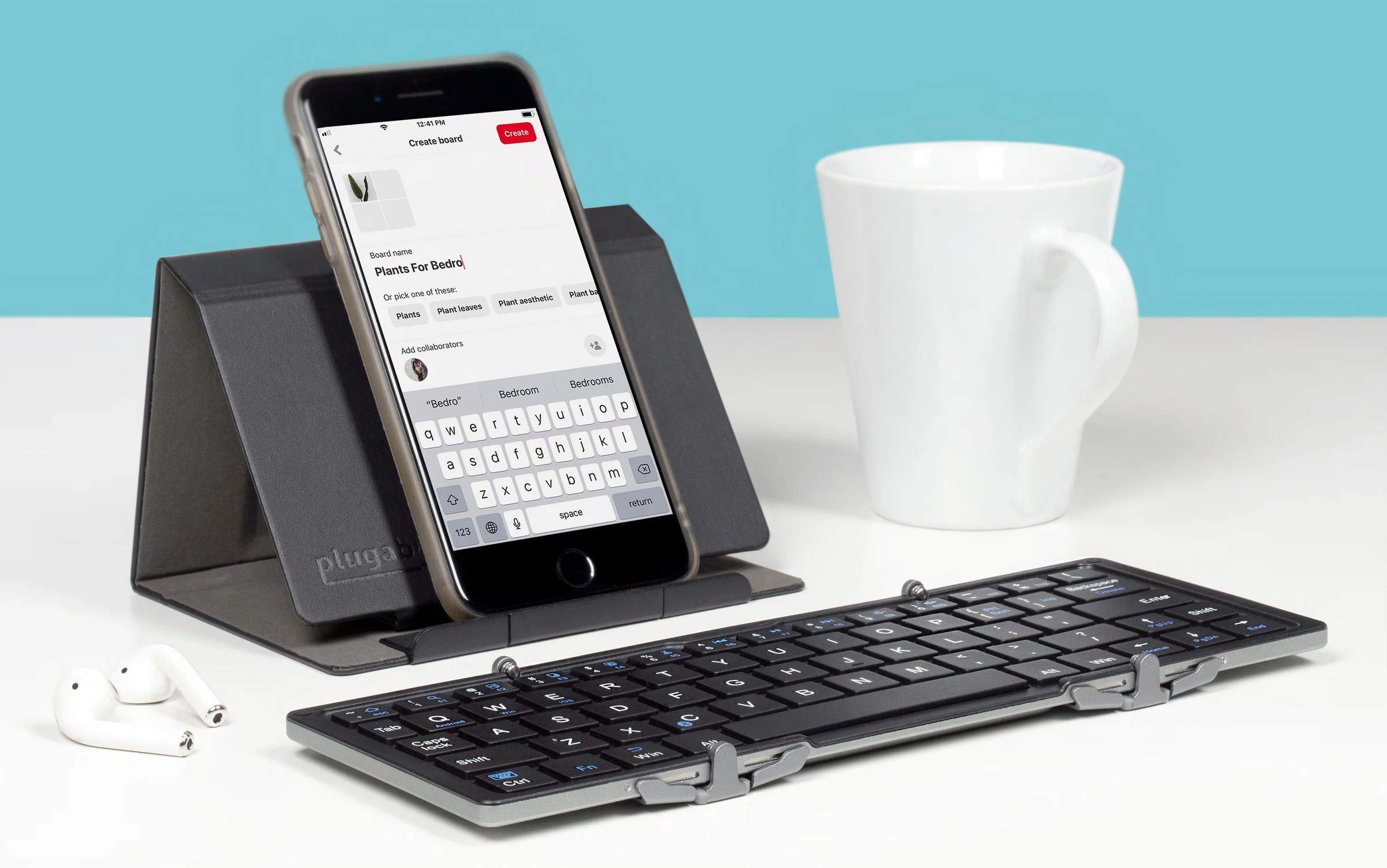 A Plugable BT-KEY3 folding keyboard sitting in front of an iPhone propped up with the included stand that doubles as a protective case for the keyboard