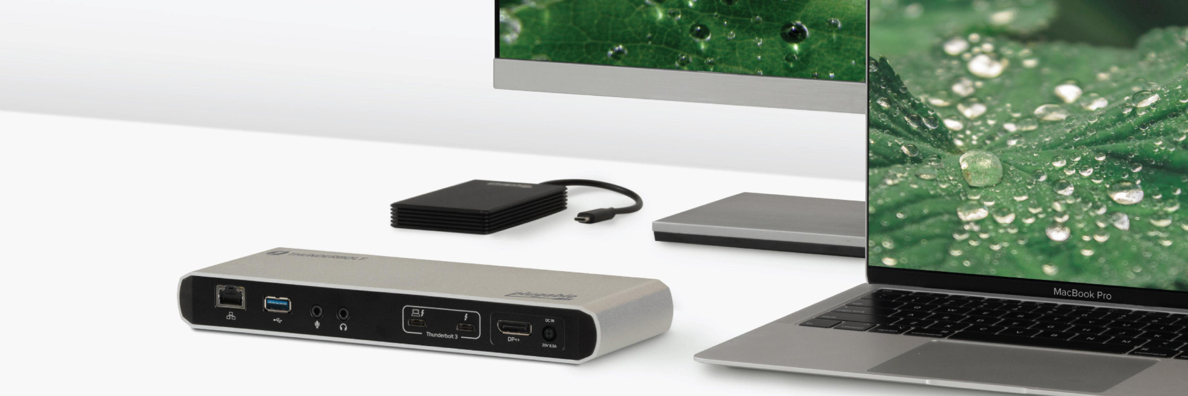 Plugable docking station and external SSD next to a laptop